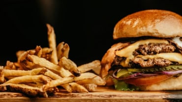 Freshly made gourmet burger with lettuce and tomato, served in a stylish restaurant setting.