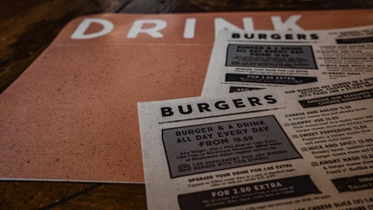 Restaurant menu on rustic wooden table highlighting Staffino's customer experience solutions.