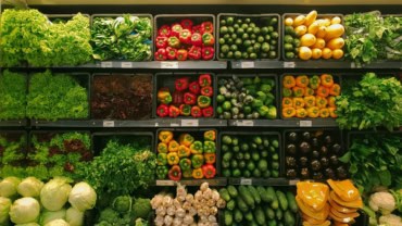 Fresh green vegetable in shopping cart at grocery store aisle in supermarket.