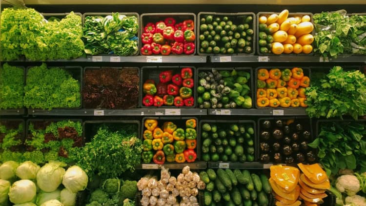 Fresh green vegetable in shopping cart at grocery store aisle in supermarket.