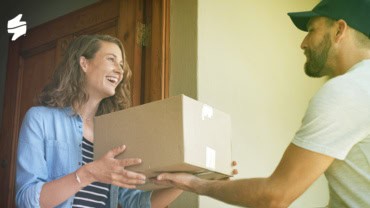 The image shows a delivery courier hand over a package to a satisfied customer.