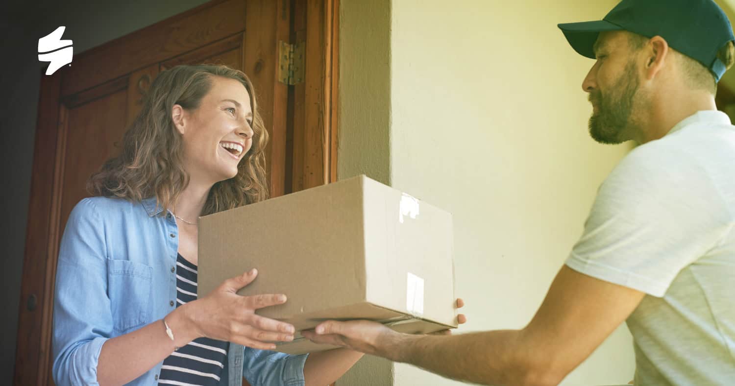 The image shows a delivery courier hand over a package to a satisfied customer.